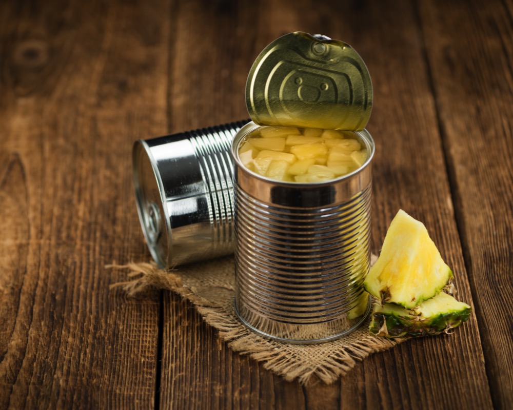 Portion of Chopped Pineapple (preserved) on wooden background, selective focus Fresh made Chopped Pineapple (preserved) on an old and rustic wooden table; selective focus; close-up shot Can Stock Photo